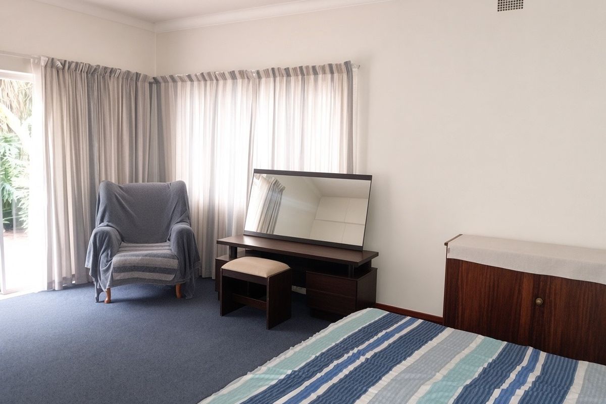 A spacious bedroom featuring blue carpeting, neutral walls, and a sliding glass door providing access to the exterior.