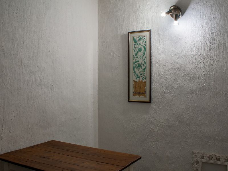 A corner view of a room featuring textured white walls and a fixed wall-mounted spotlight fixture.