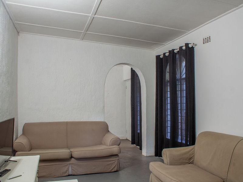 A living room featuring an arched doorway, security gate, and textured walls, offering a functional space with potential for cosmetic updates.