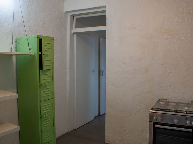 A functional kitchen area featuring a gas stove, oven, and built-in shelving, with access to adjacent rooms through a doorway.