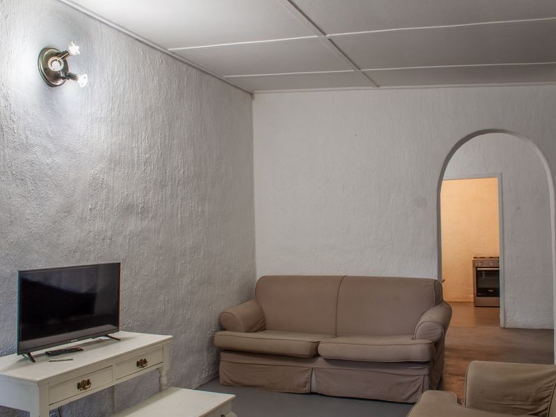 A living room featuring textured walls, a tiled ceiling, and an arched doorway leading to an adjacent kitchen area.