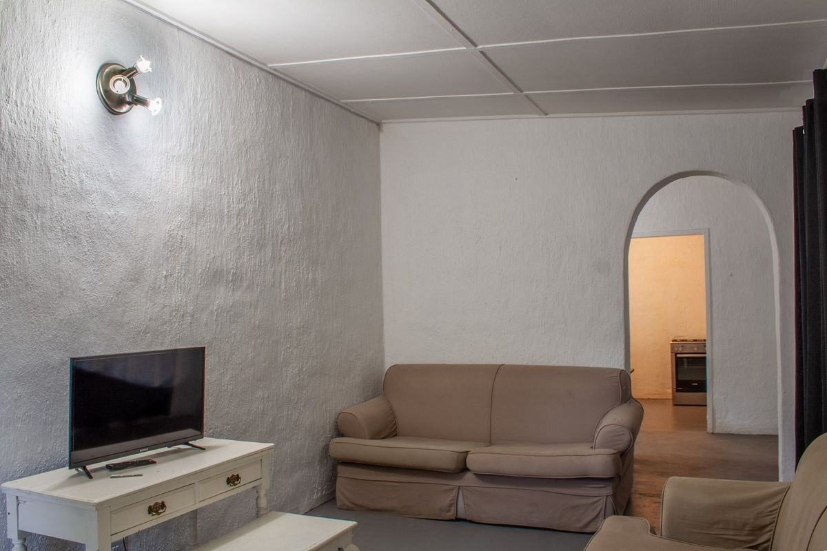 A living room featuring textured walls, a tiled ceiling, and an arched doorway leading to an adjacent kitchen area.