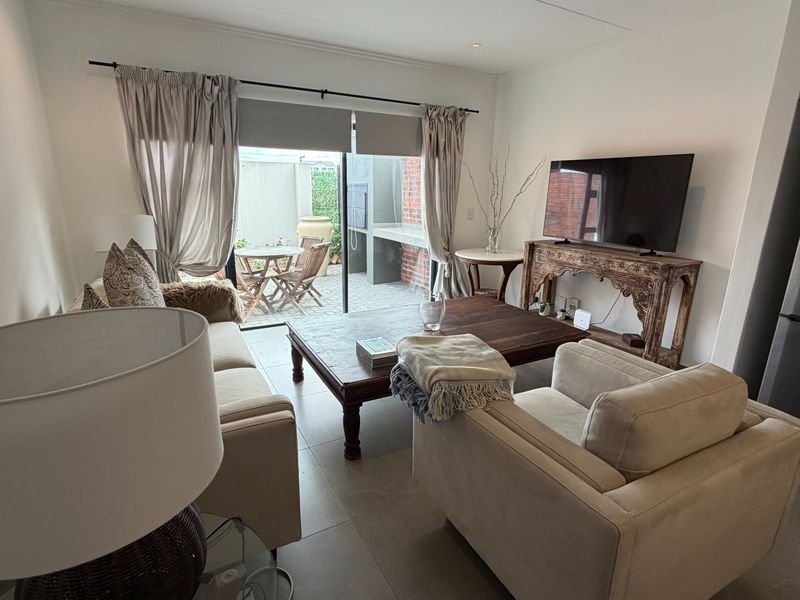 A comfortable living room featuring tiled flooring and a large sliding glass door that provides direct access to an outdoor patio area.