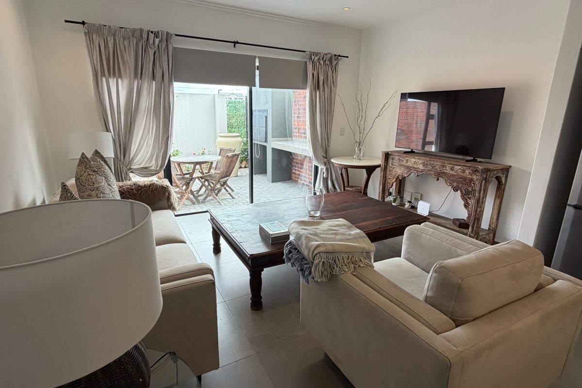 A comfortable living room featuring tiled flooring and a large sliding glass door that provides direct access to an outdoor patio area.