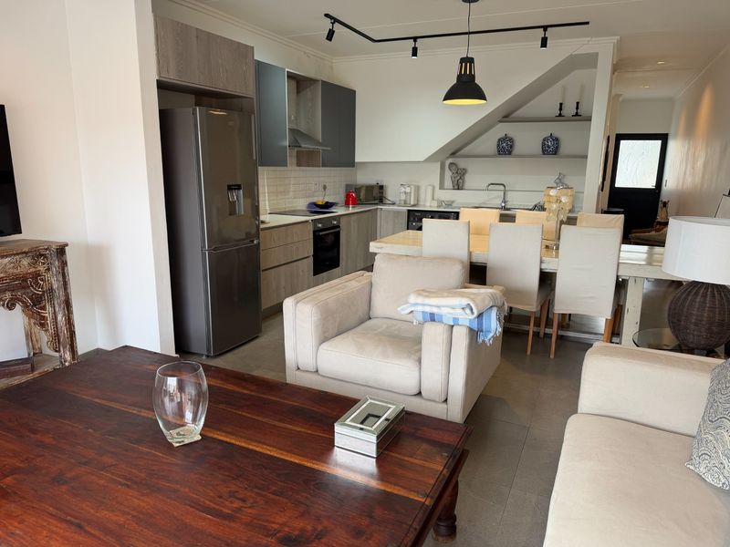 Open-plan living and dining area featuring a modern kitchen with built-in cabinetry, integrated appliances, and sleek tiled flooring throughout.