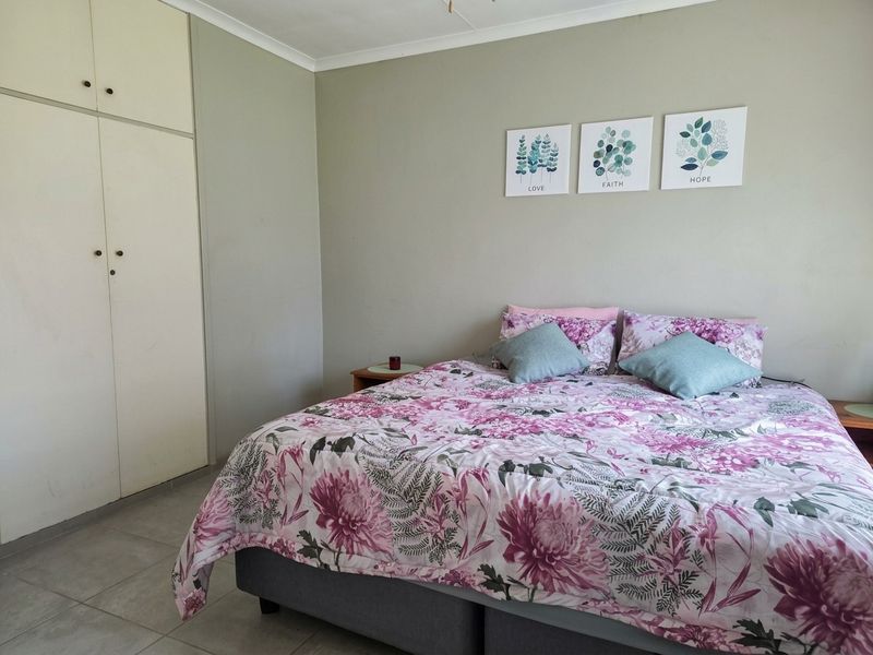 A functional bedroom featuring built-in cupboards, neutral wall tones, and tiled flooring, providing a clean and practical living space.