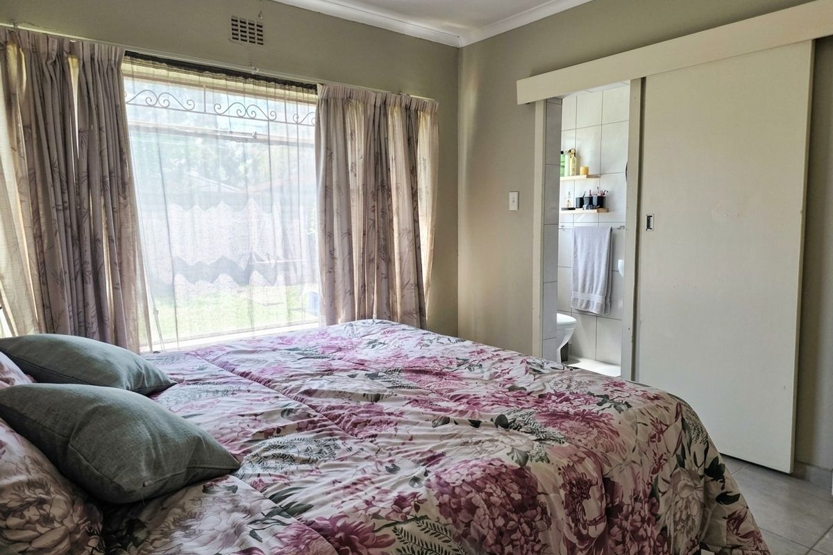 A bedroom featuring a window with security bars and a sliding door providing access to an en-suite bathroom.