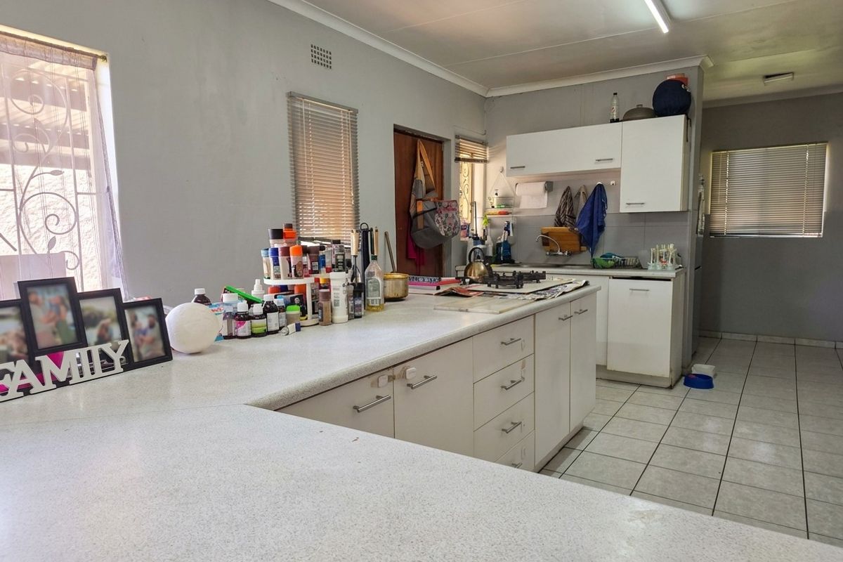 Functional kitchen featuring white built-in cabinetry, laminate countertops, a gas hob, and ceramic floor tiles, offering a practical layout for daily meal preparation.