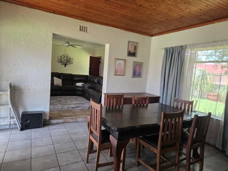 Dining room featuring tiled flooring and a timber ceiling, with an open-plan transition to the adjacent living area.