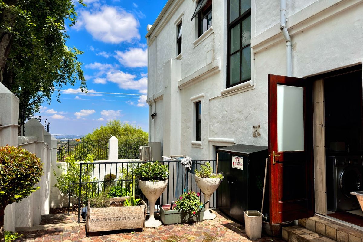 A rear courtyard area featuring brick paving, wrought iron railings, and access to the main dwelling through a timber door.
