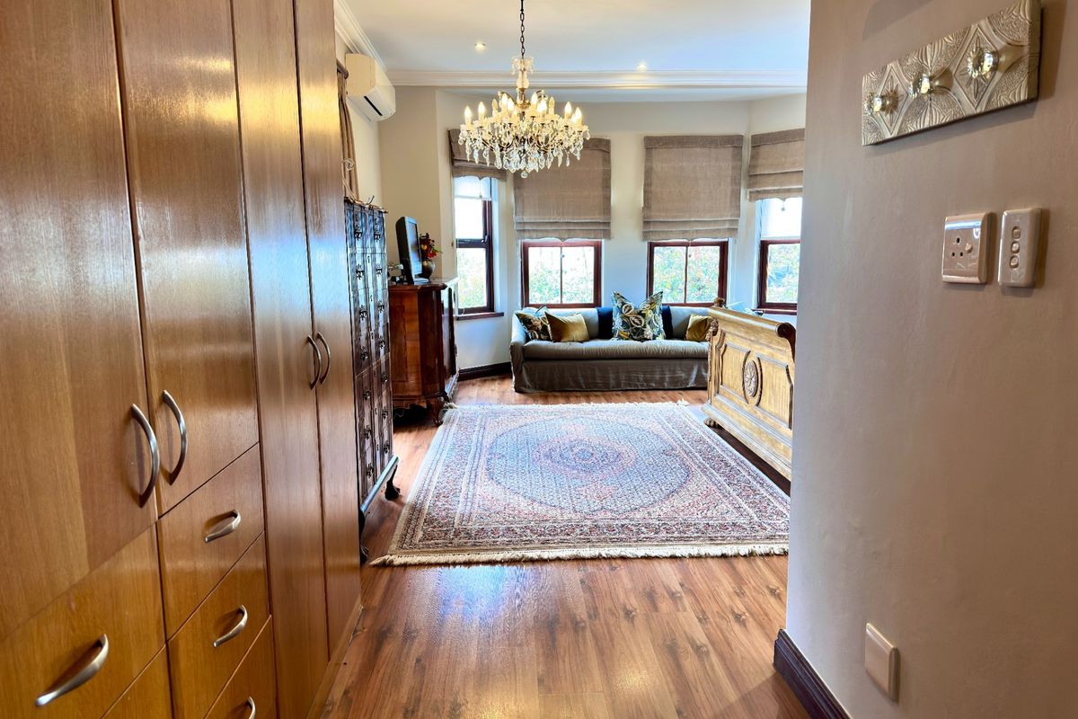 Spacious bedroom featuring extensive built-in cabinetry, laminate flooring, and a classic chandelier, offering a comfortable and well-maintained living space.