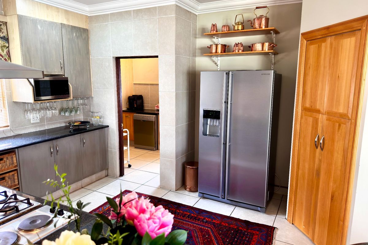 Modern kitchen featuring granite countertops, built-in cabinetry, and a dedicated scullery area, finished with tiled flooring and crown molding.