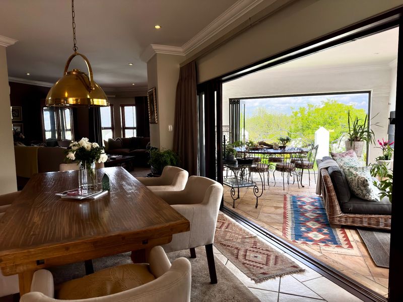Spacious open-plan dining area featuring elegant pendant lighting and large sliding glass doors that open onto a covered patio with scenic views.