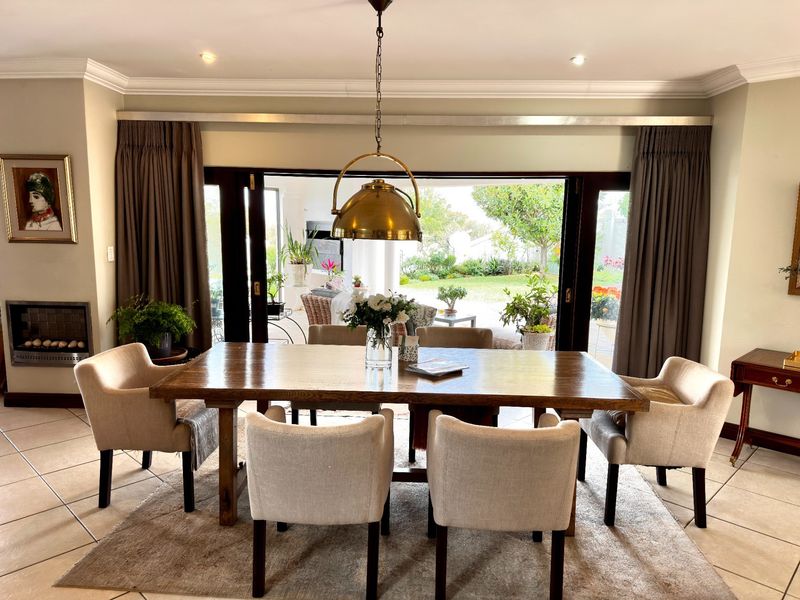 Elegant dining room featuring tiled floors, crown molding, a built-in fireplace, and large sliding doors opening to a garden patio.