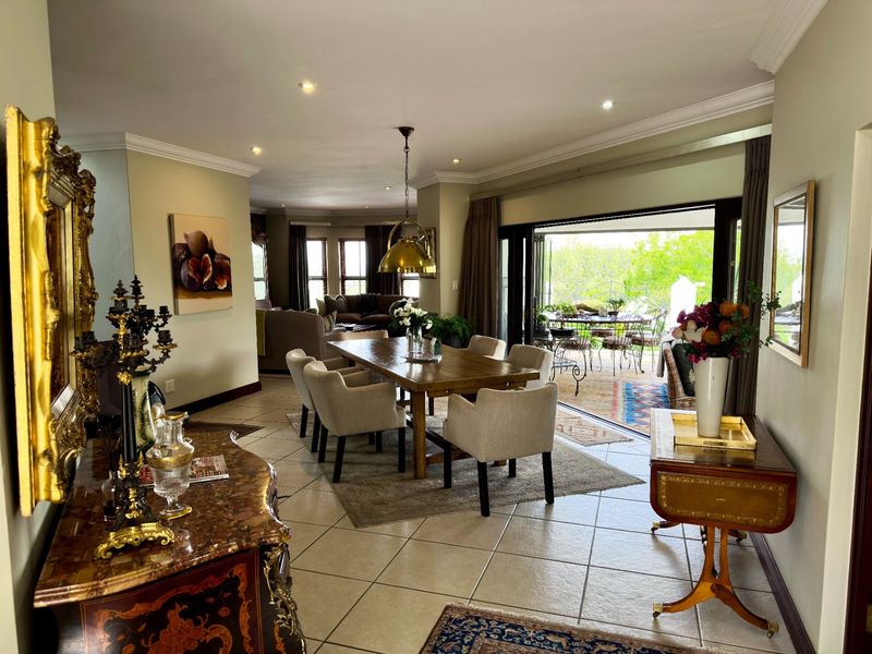 Spacious open-plan dining area featuring tiled floors, recessed lighting, and large stacking doors that provide seamless access to the outdoor patio.