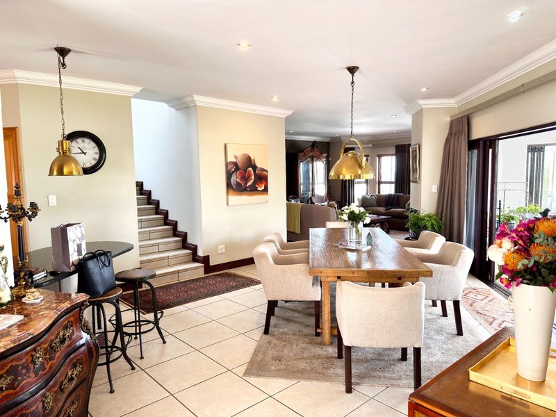 Spacious open-plan dining and living area featuring tiled floors, elegant pendant lighting, and direct access to the outdoor patio through sliding glass doors.