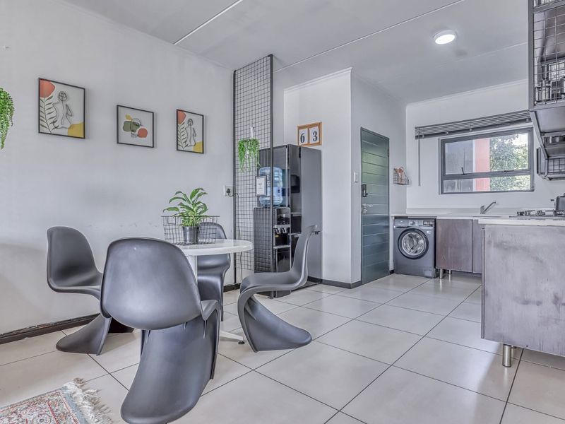 An open-plan living and kitchen area featuring tiled flooring, modern cabinetry, and integrated appliances, creating a functional and cohesive living space.