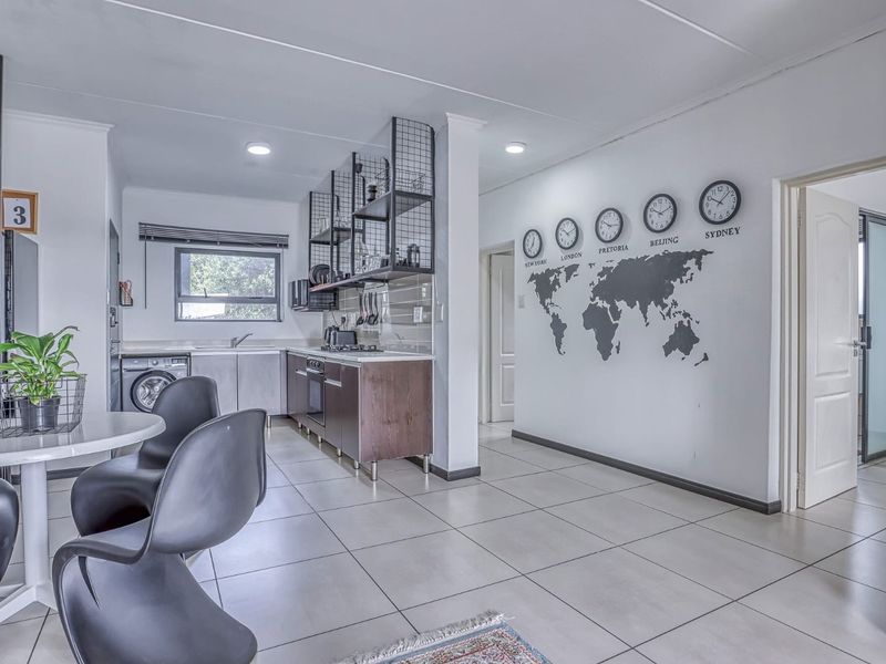 Open-plan kitchen and dining area featuring modern cabinetry, built-in appliances, tiled flooring, and recessed lighting in a functional apartment layout.