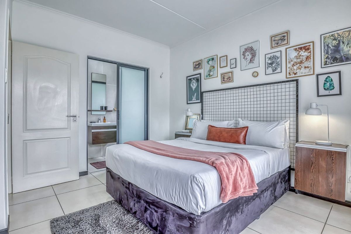 A well-maintained bedroom featuring tiled flooring and an integrated en-suite bathroom with a modern vanity unit.