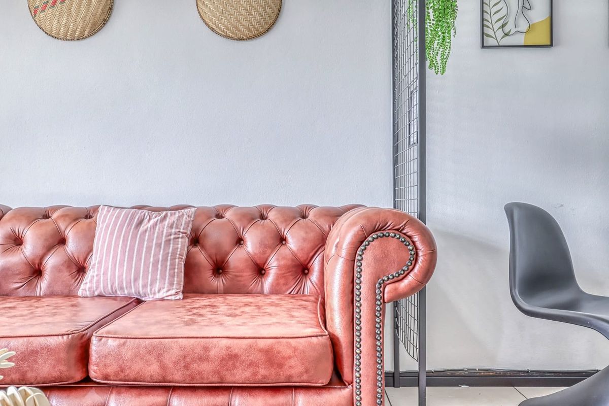 A close-up view of a living room area featuring a tufted leather sofa against a neutral wall.
