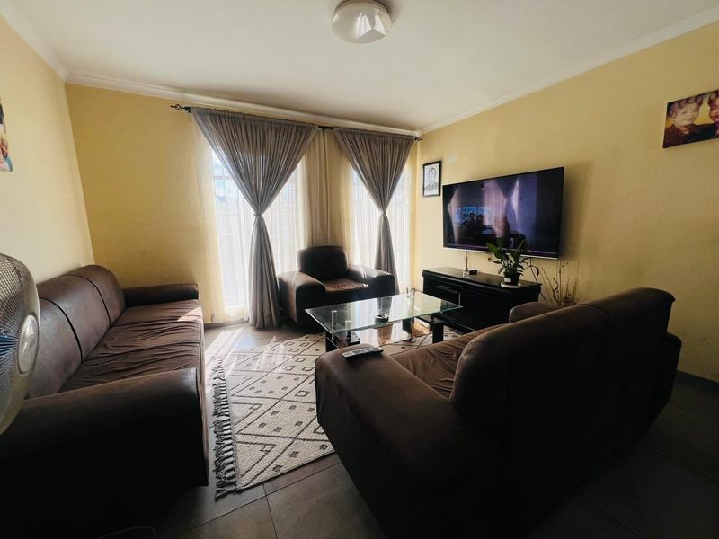 A comfortable living room featuring tiled flooring and natural light through large windows, providing a functional space for relaxation.