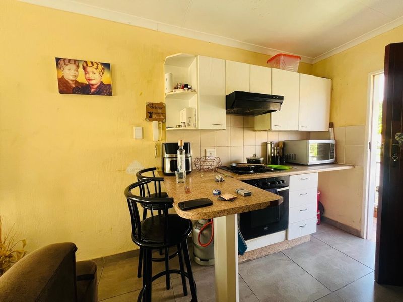 Compact kitchen featuring built-in cabinetry, laminate countertops, a built-in oven with hob, and tiled flooring, offering a functional layout for daily meal preparation.