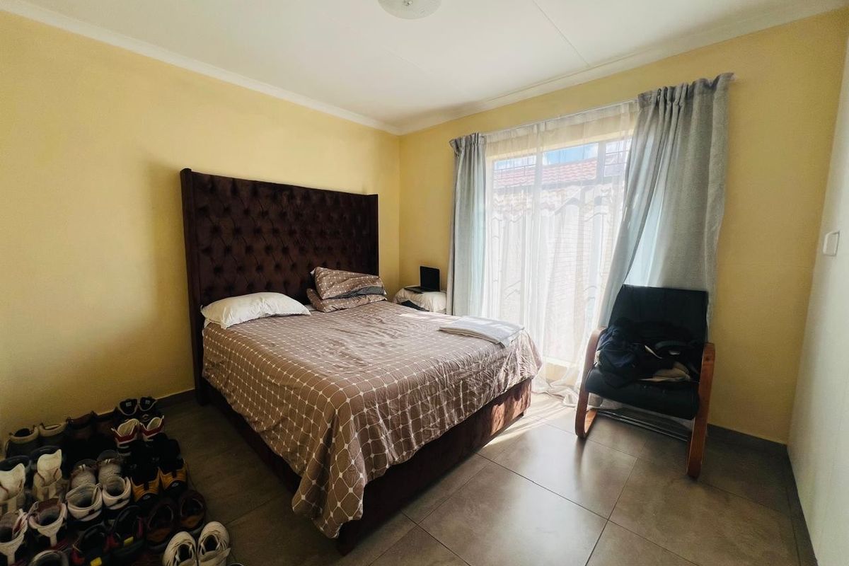 A bedroom featuring tiled flooring and a sliding glass door providing natural light.
