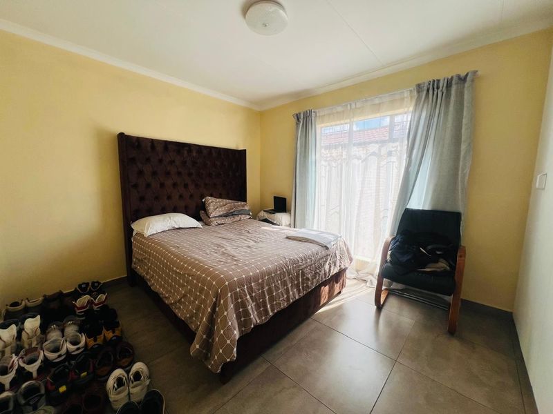 A bedroom featuring tiled flooring and a sliding glass door providing natural light.