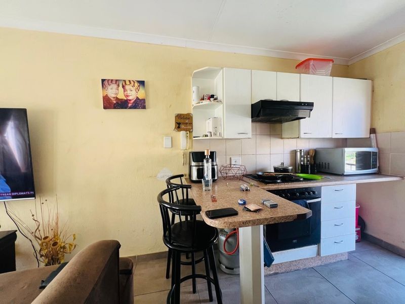 Open-plan kitchen area featuring built-in cabinetry, a breakfast counter, and integrated cooking appliances, requiring cosmetic updates to improve the overall aesthetic.