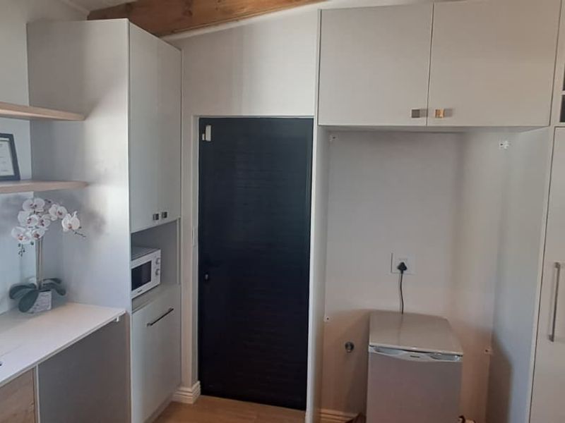 A modern kitchen featuring light-toned cabinetry, built-in microwave, wine storage, and a clean tiled splashback with an undermount sink.