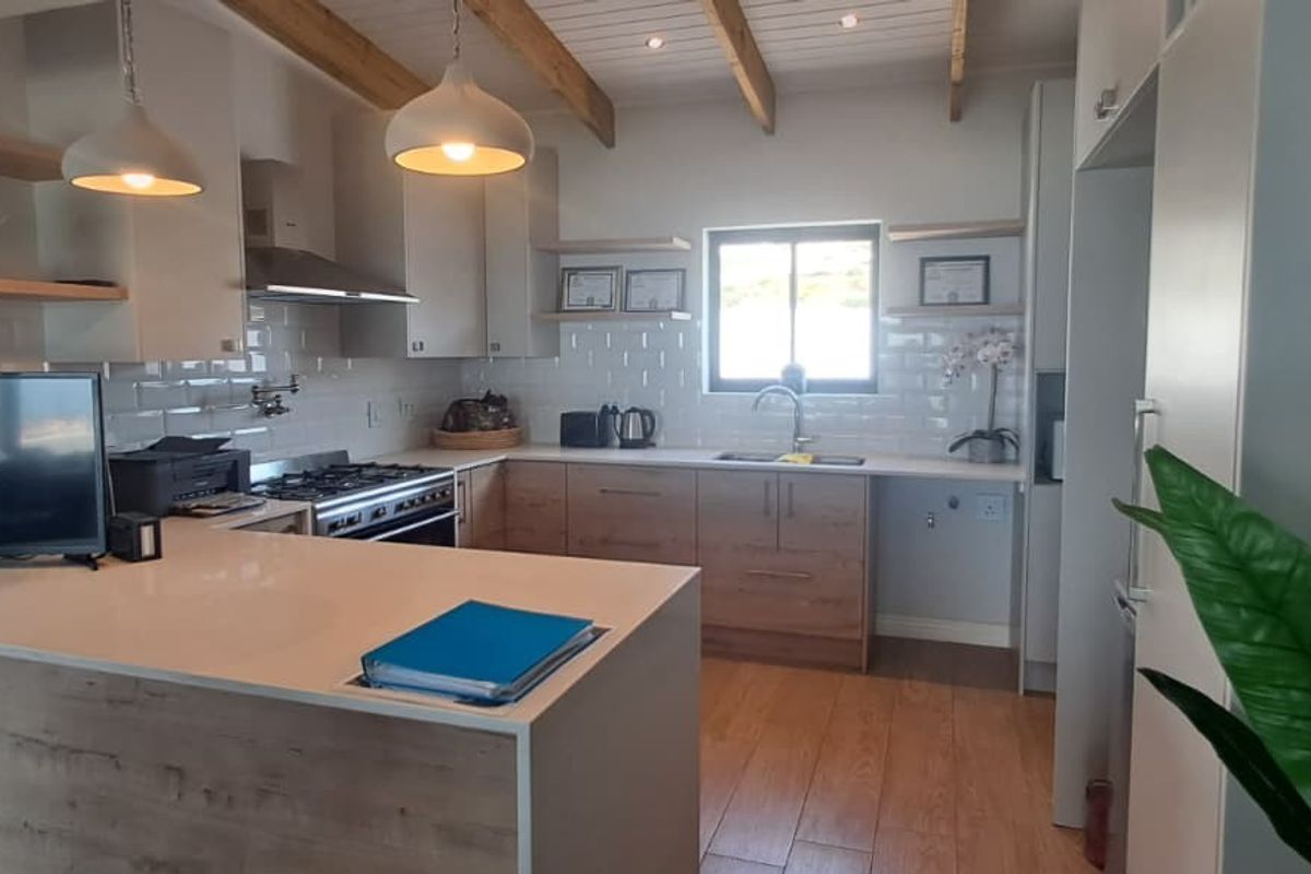 Modern kitchen featuring timber-look cabinetry, quartz countertops, subway tile backsplash, gas hob, and exposed timber ceiling beams.