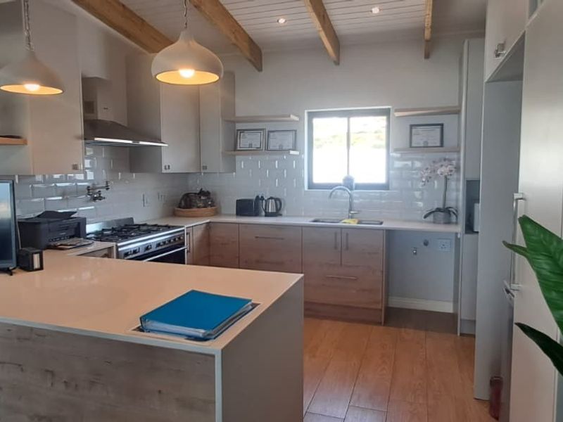 Modern kitchen featuring timber-look cabinetry, quartz countertops, subway tile backsplash, gas hob, and exposed timber ceiling beams.