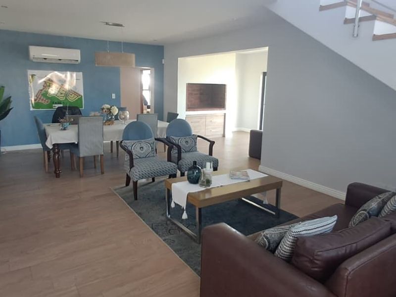 Spacious open-plan living and dining area featuring laminate flooring, recessed lighting, and a modern staircase with a stainless steel balustrade.