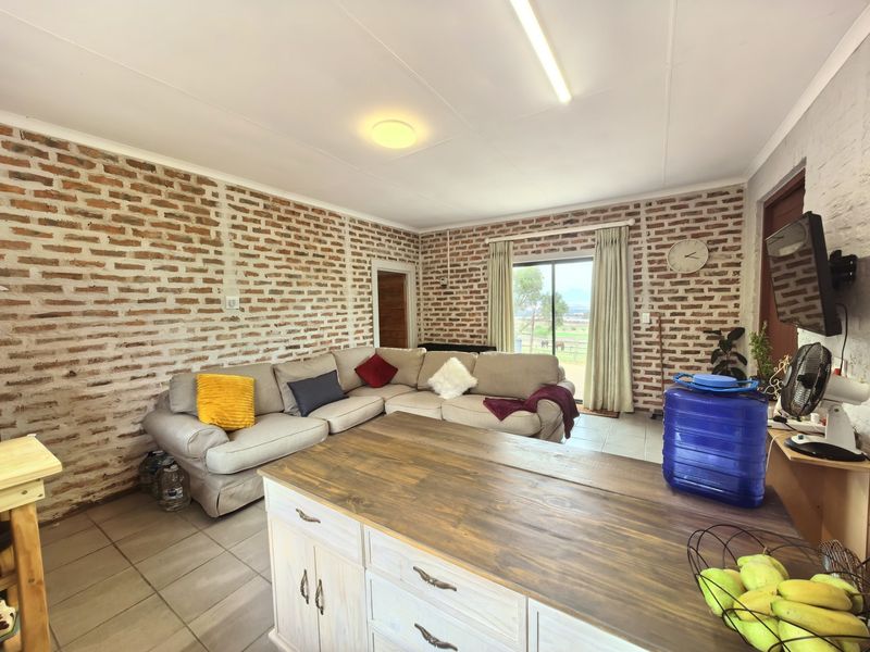 Open-plan living area featuring rustic exposed brick walls, tiled flooring, and a sliding glass door providing natural light and garden access.