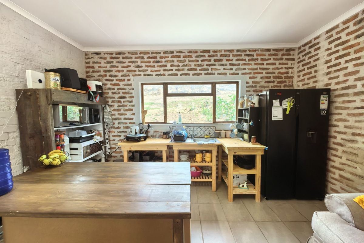 Rustic kitchen featuring exposed brick walls, tiled flooring, and timber work surfaces with a functional sink area and window view.