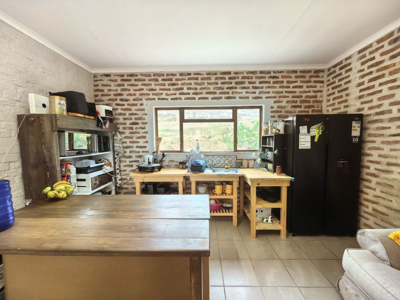 Rustic kitchen featuring exposed brick walls, tiled flooring, and timber work surfaces with a functional sink area and window view.