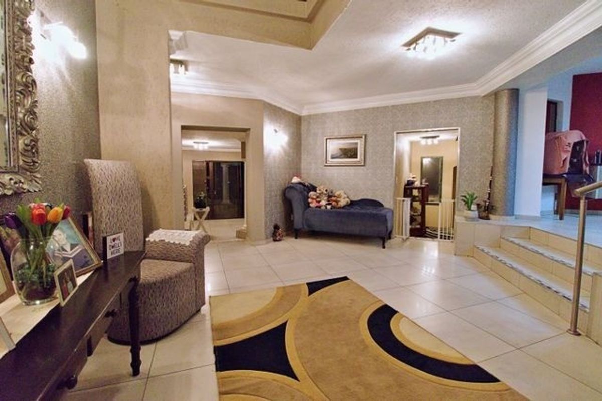 Spacious living area featuring tiled flooring, recessed ceiling details, and an open-plan layout with an elegant archway leading to adjacent spaces.