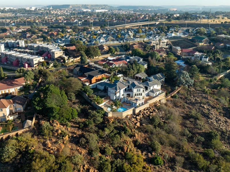 An elevated aerial view of the property, showcasing its position within the estate, including the swimming pool and surrounding landscape.