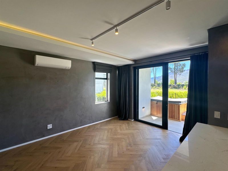 Modern open-plan living area featuring herringbone timber flooring, recessed lighting, split-system air conditioning, and direct access to a private balcony with mountain views.
