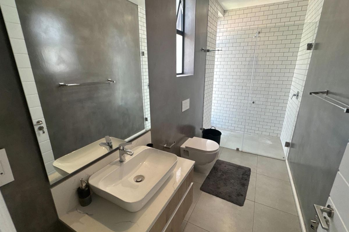 Modern bathroom featuring a wall-mounted vanity with vessel sink, wall-hung toilet, and a spacious walk-in shower with white subway tiling.