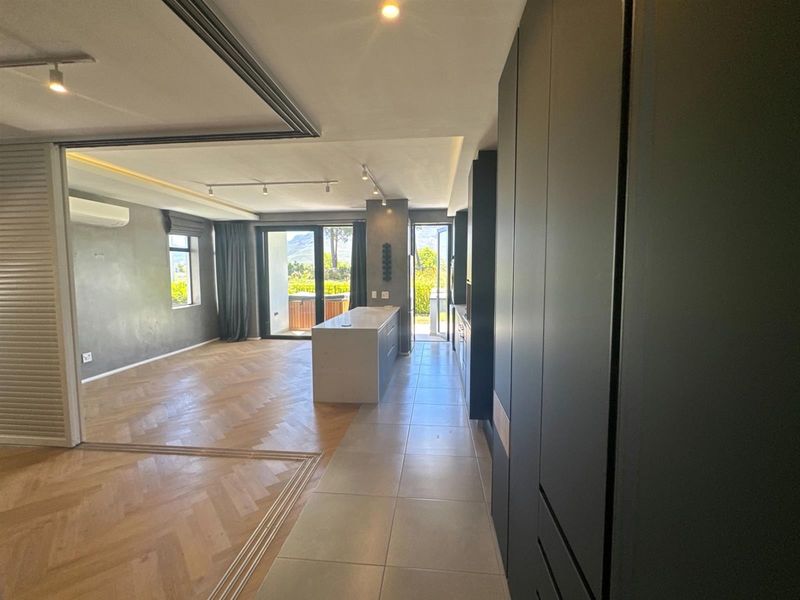 Spacious open-plan living and kitchen area featuring herringbone timber floors, modern cabinetry, a central island, and large sliding doors leading to an outdoor space.