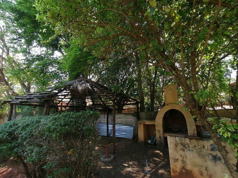 Outdoor garden area featuring a built-in braai and a wooden gazebo structure in need of maintenance and repair.