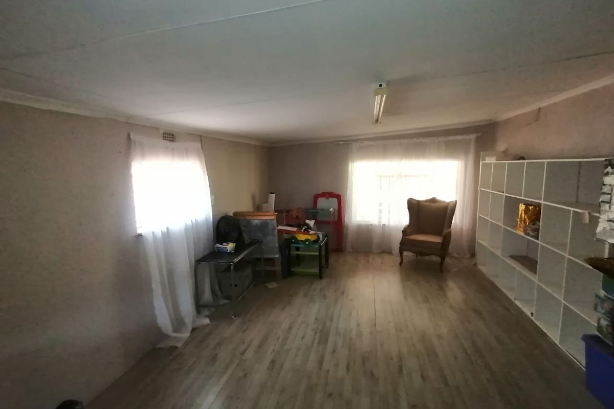 A living area featuring laminate flooring and a fluorescent light fixture, requiring cosmetic updates to improve the overall aesthetic and finish.