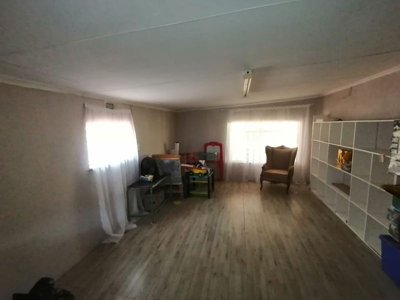 A living area featuring laminate flooring and a fluorescent light fixture, requiring cosmetic updates to improve the overall aesthetic and finish.