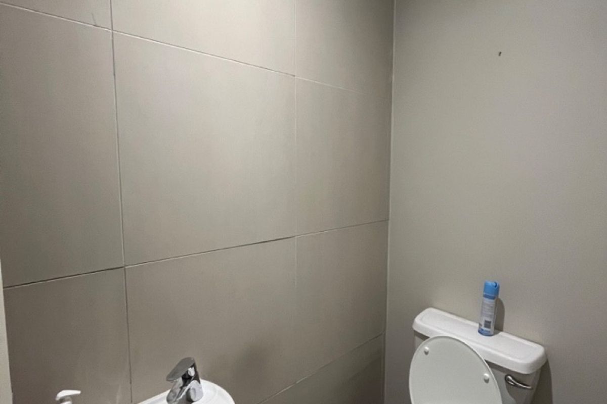 A compact, functional bathroom featuring a pedestal sink, toilet, and neutral wall tiling.