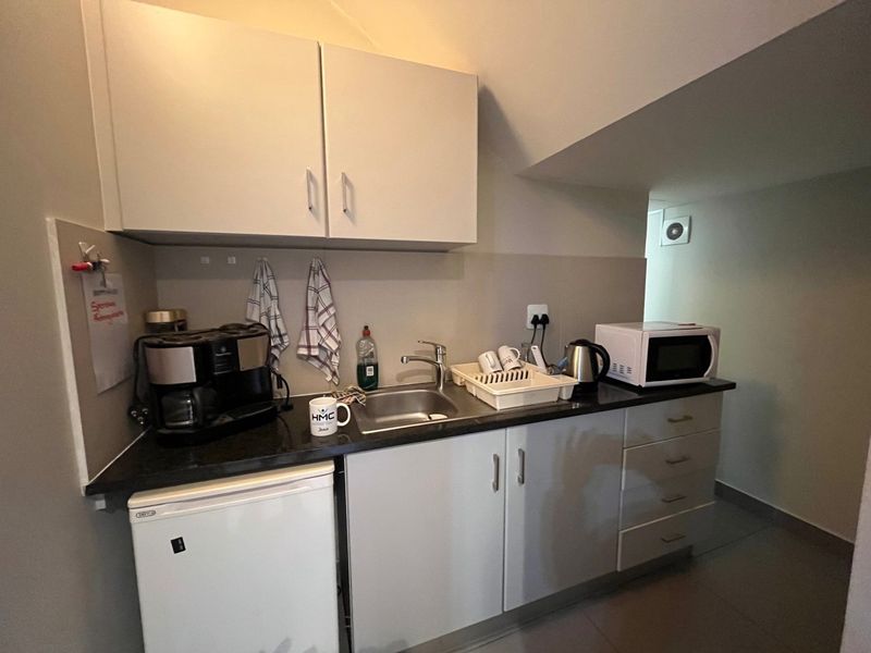Compact industrial scullery area featuring built-in cabinetry, a stainless steel sink, and a functional countertop workspace.