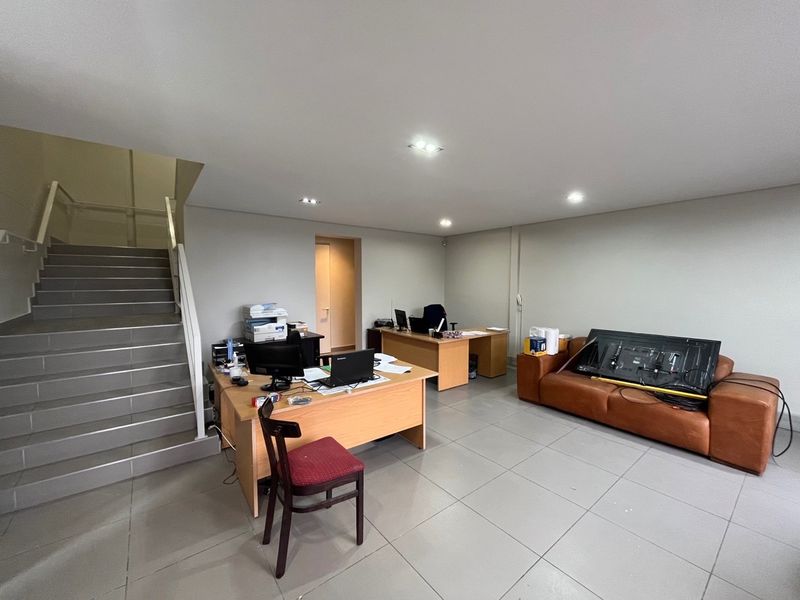 A functional office space featuring tiled flooring, recessed lighting, and an integrated staircase leading to an upper level.