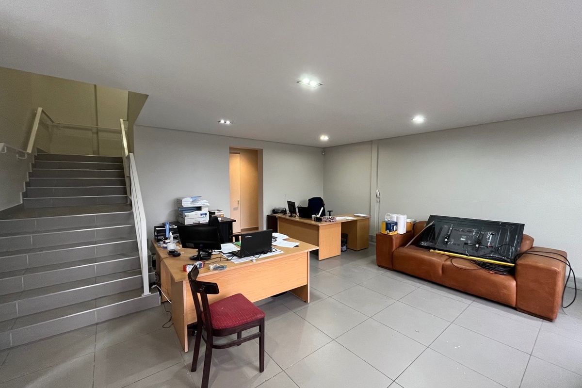 A functional office space featuring tiled flooring, recessed lighting, and an integrated staircase leading to an upper level.