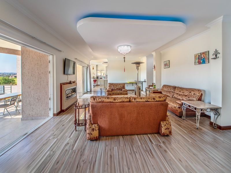 Spacious open-plan living area featuring a modern recessed ceiling with accent lighting, built-in fireplace, and large sliding doors leading to an outdoor patio.