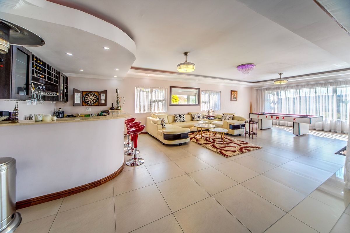 Spacious open-plan living area featuring a built-in bar counter, tiled flooring, and recessed ceiling lighting, offering a versatile entertainment space.